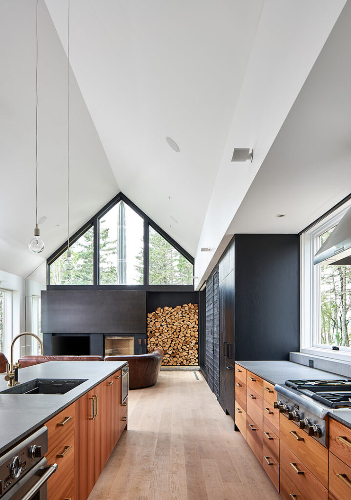 Shot of a kitchen into living area, featuring artfully stacked firewood from the recent kitchen cabinet project in L'Etete, New Brunswick.