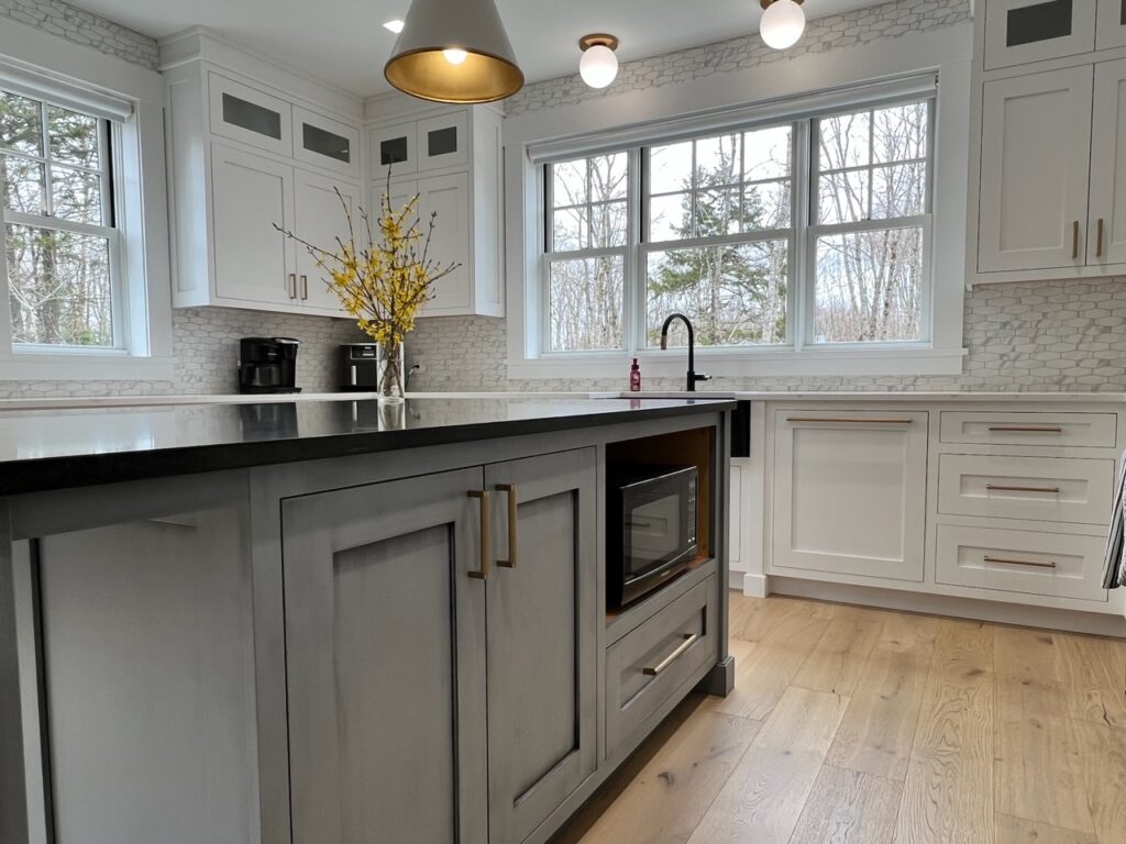 Grey island with a built-in microwave and black countertop in a white kitchen