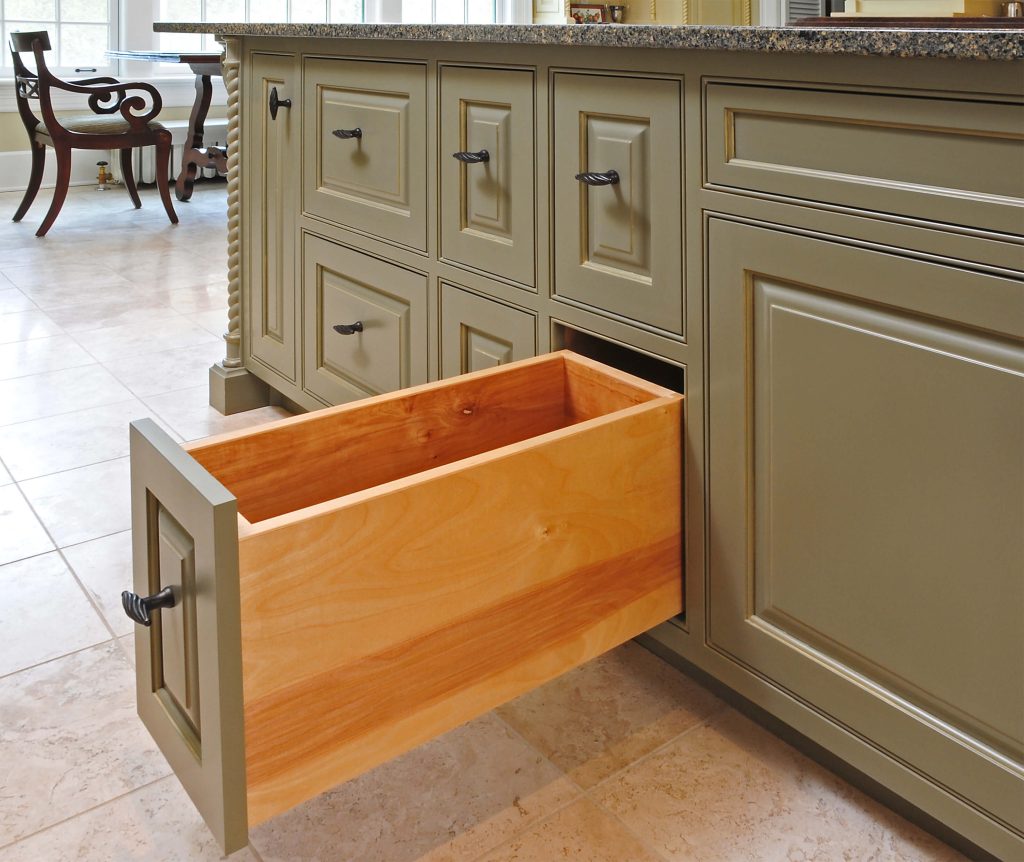 Open drawer in a sage green island showing its wood box