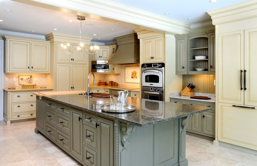 Sage green island with carved corbels in a cream kitchen with a built-in wall oven