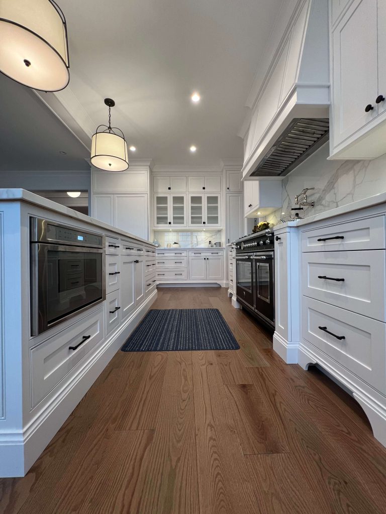 White kitchen with a built-in microwave drawer, glass-front uppers and a marble backsplash