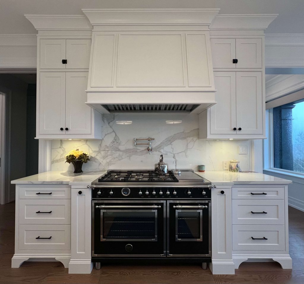 White range wall with a black range, marble backsplash and a pot filler