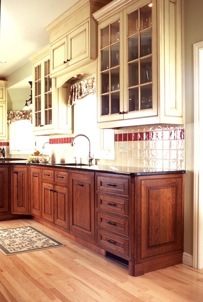 Two-tone kitchen with cream glass-front uppers and cherry base cabinets