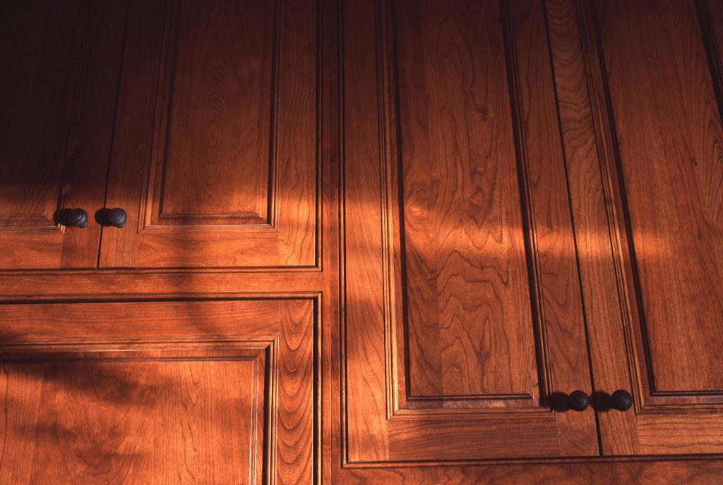 Close view of cherry raised-panel doors with dark knobs