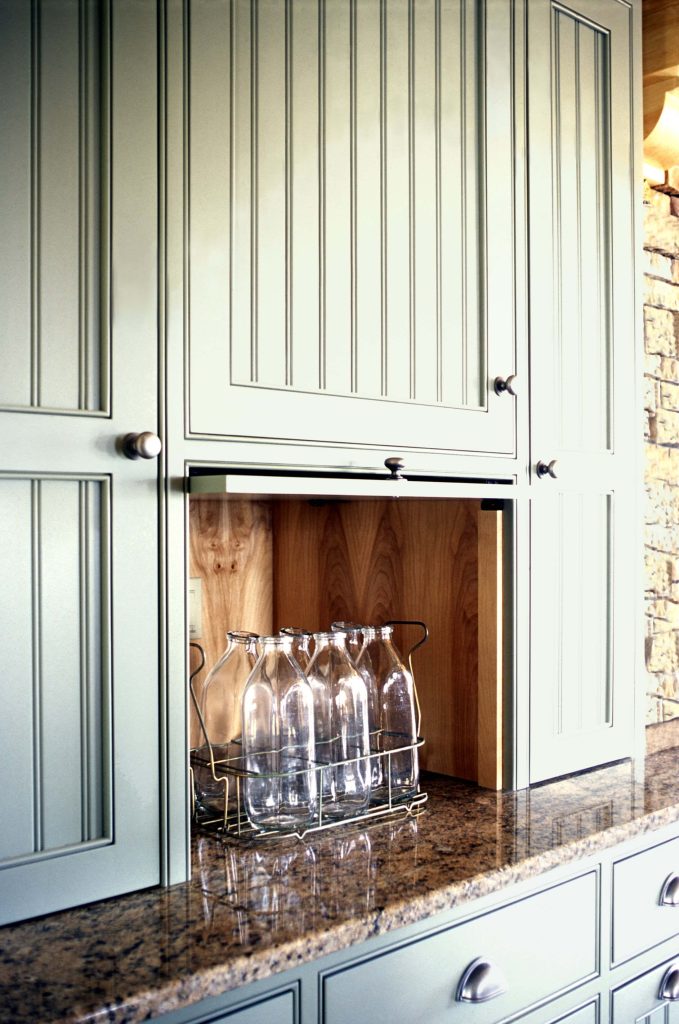 Appliance garage with a lift-up door in a sage green beadboard cabinet