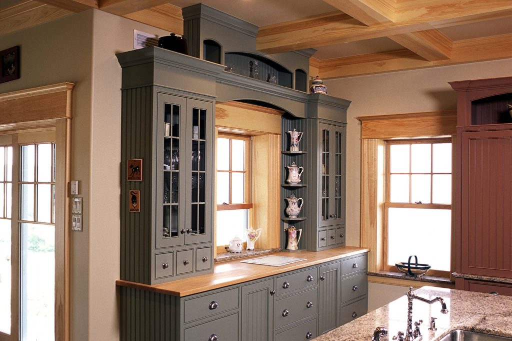Blue-grey hutch with glass doors in a kitchen with a coffered wood ceiling