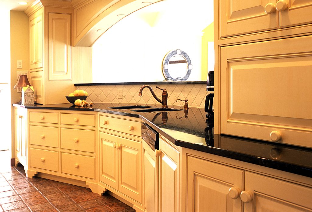 Cream kitchen with a black granite countertop and a corner sink