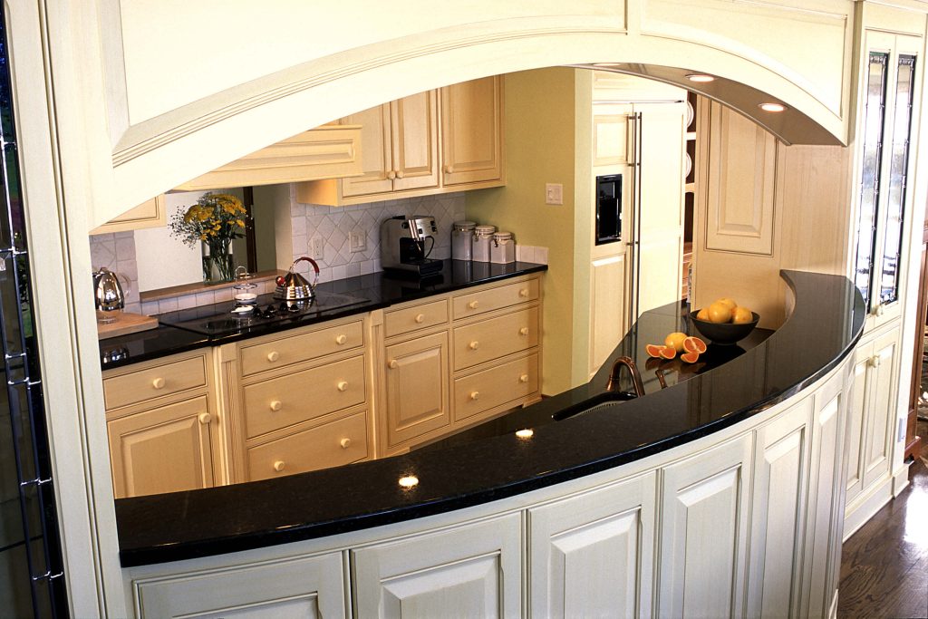 Cream kitchen with a curved black countertop under an arched soffit