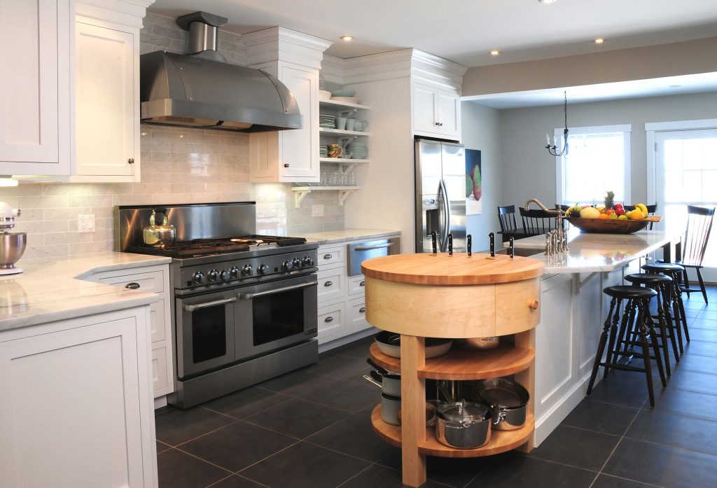 White kitchen with a round maple butcher-block island and a stainless range