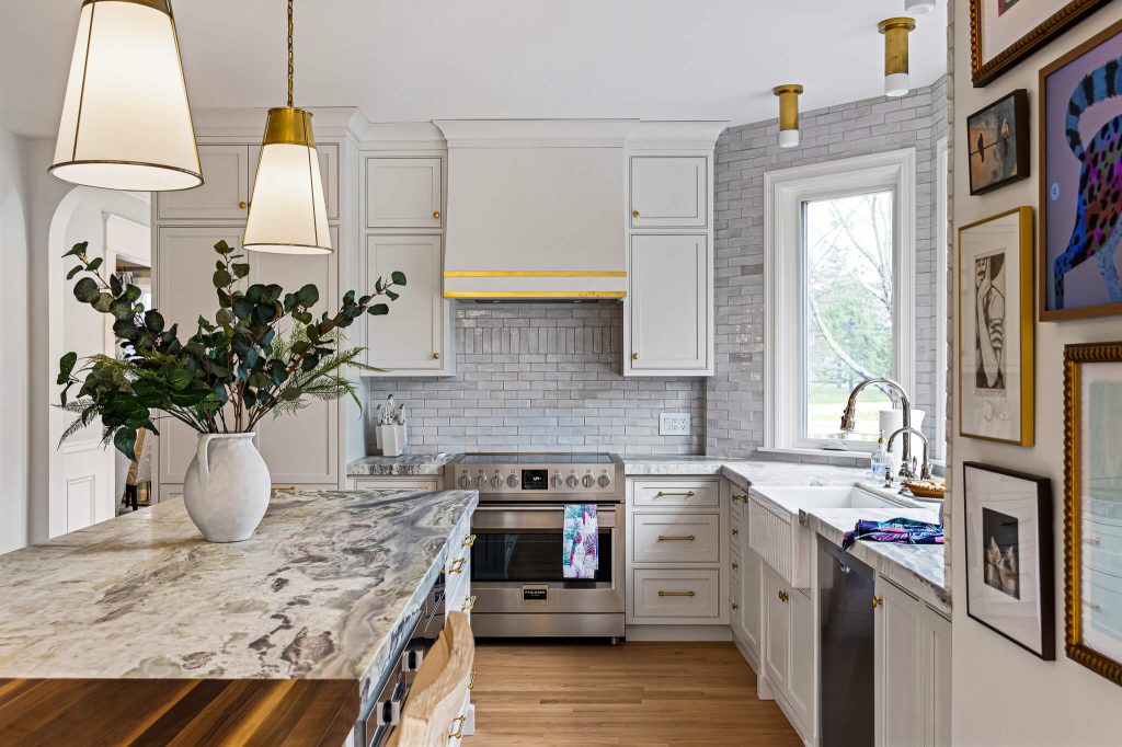 White kitchen with a range wall, farmhouse sink and marble-topped island