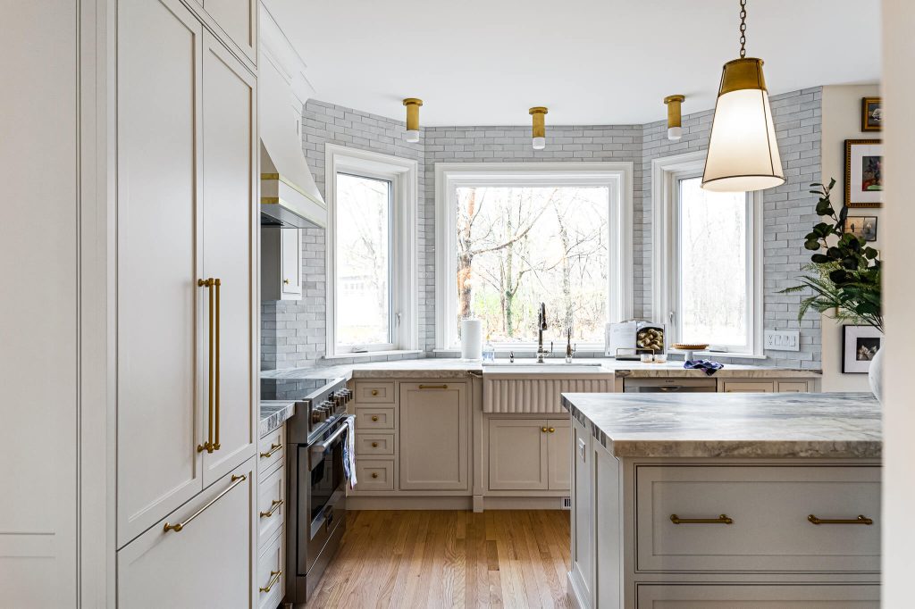 Integrated panel refrigerator and white cabinetry around a marble-topped island