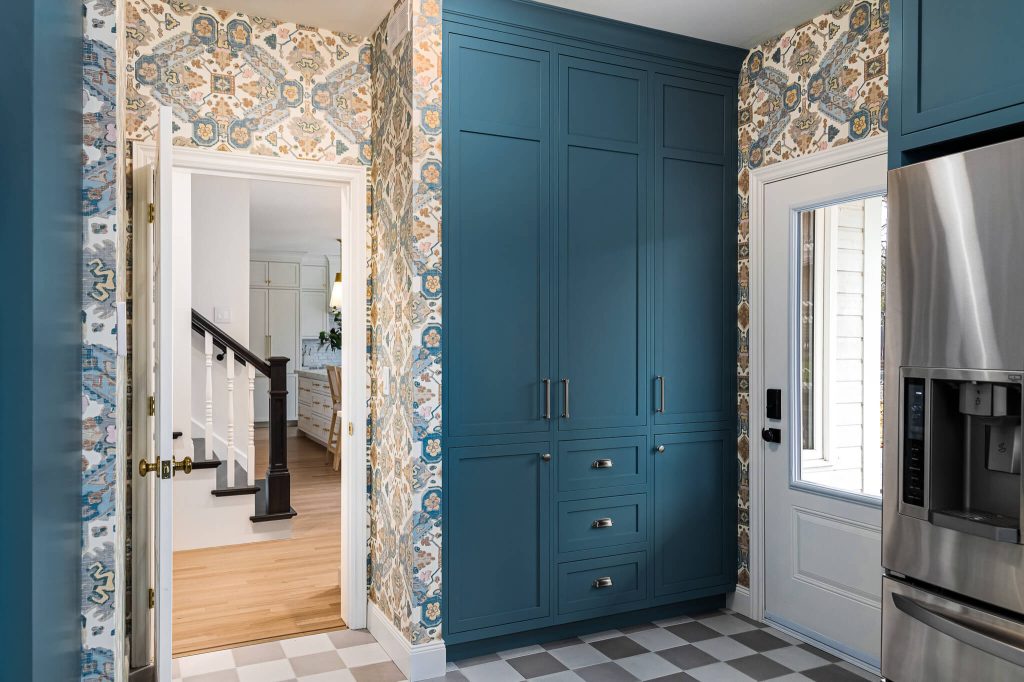 Teal floor-to-ceiling cabinets beside a patterned wallpaper wall