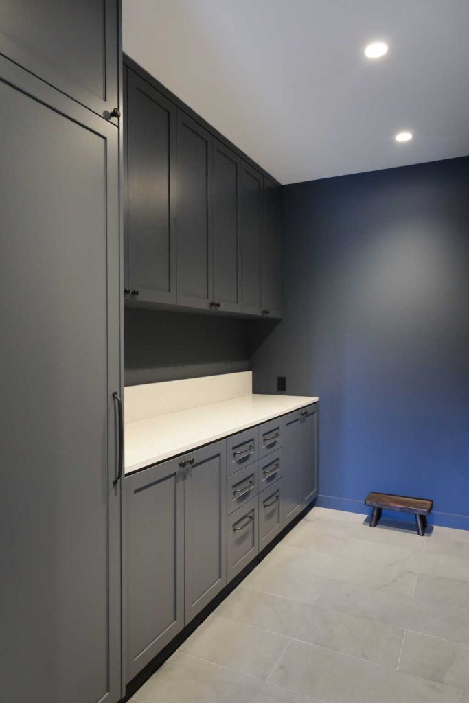 Charcoal floor-to-ceiling cabinets and a counter in a navy utility room