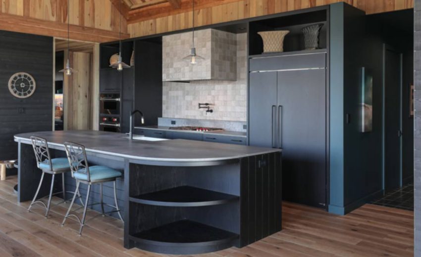 Custom kitchen cabinetry with dark millwork, integrated appliances, and curved island at St. Croix Residence