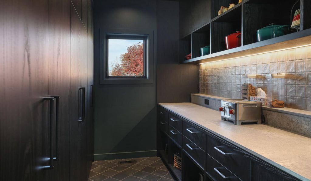 Custom pantry cabinetry with open shelving, integrated lighting, and stone countertop at St. Croix Residence