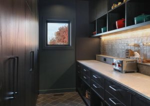 Custom pantry cabinetry with open shelving, integrated lighting, and stone countertop at St. Croix Residence